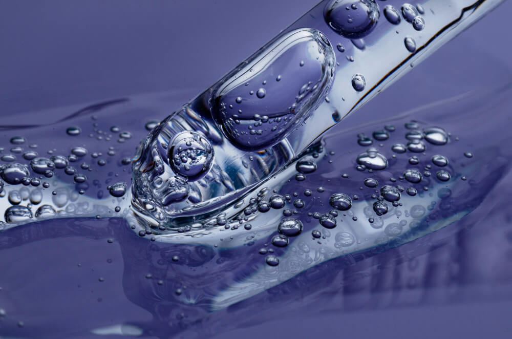 Rainwater nemlendirici serum damlalık, mor sıvı üzerinde berrak damlalar, cilt bakımı için yenileyici formül.