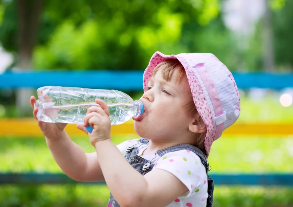 Rainwater marka su içen çocuk, yaz günü parkta serinliyor.