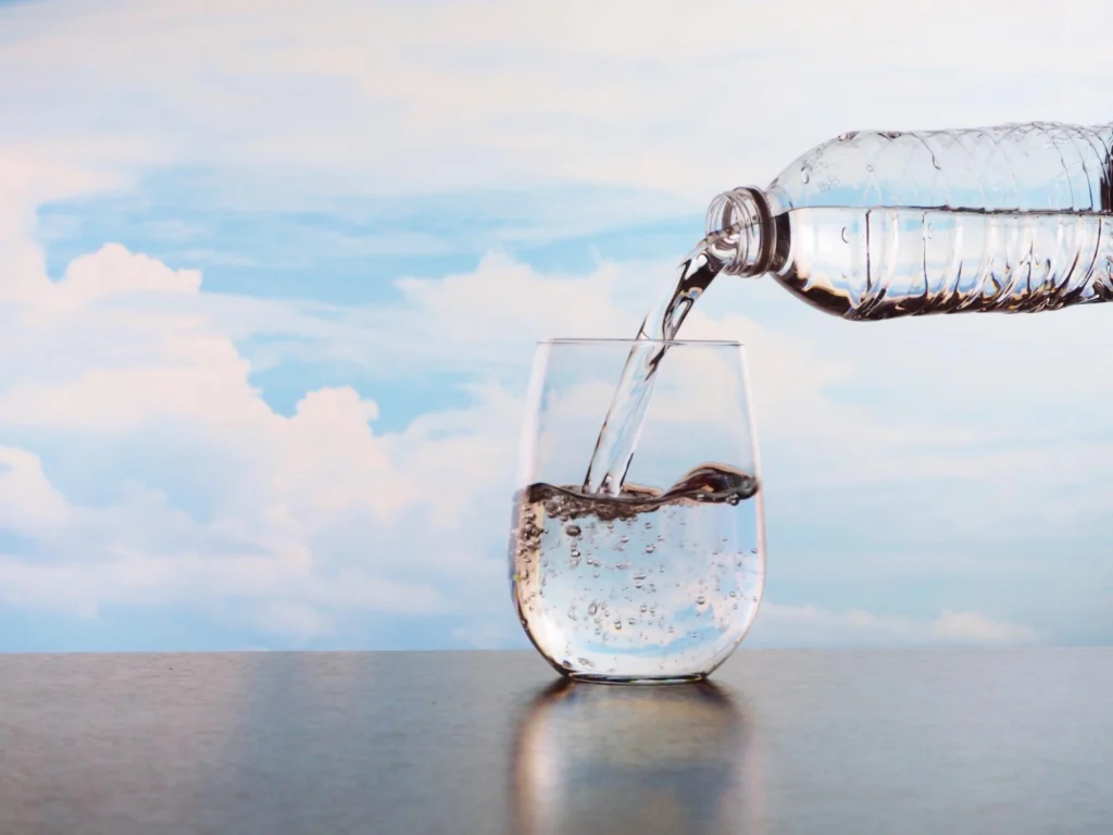 Rainwater şişesinden bardağa su dökülüyor, kaliteli doğal içme suyu.