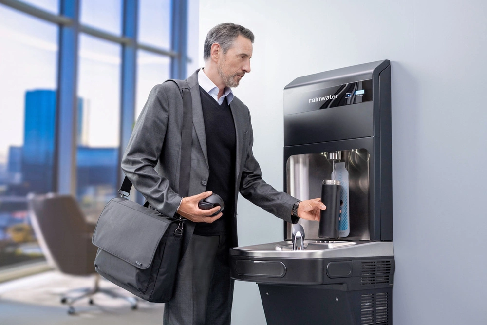Rainwater şişe doldurma istasyonu kullanarak su dolduran takım elbiseli iş adamı.